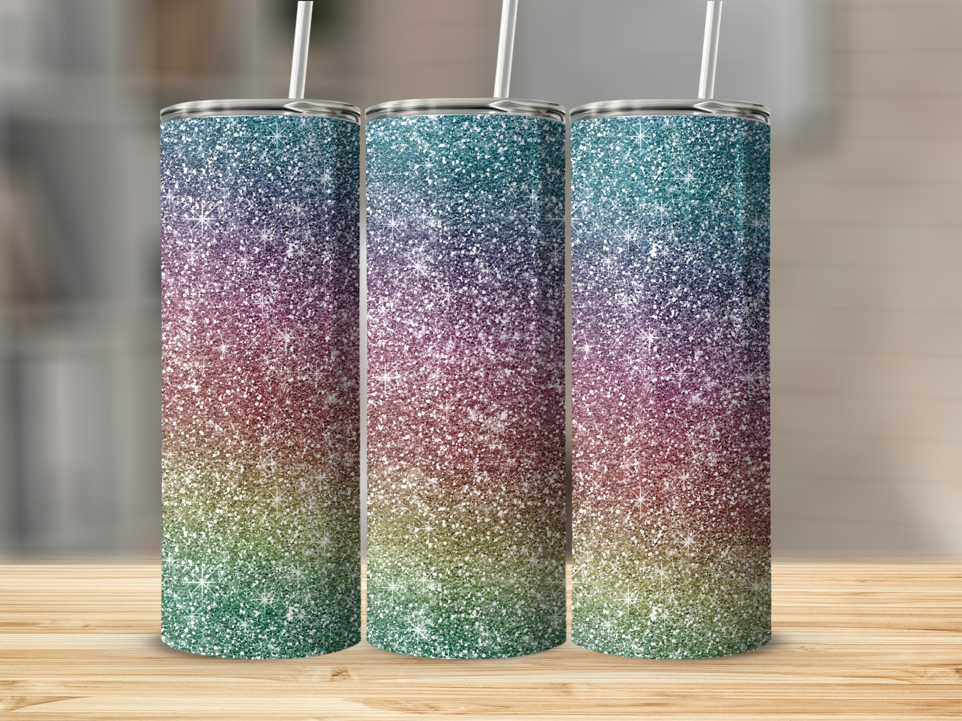 Three glitter tumblers with rainbow ombre design and white straws on a wooden surface.