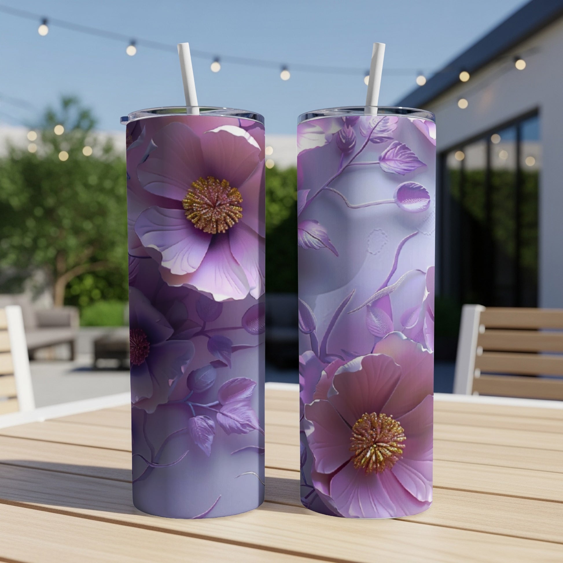 Two purple floral tumblers with straws on a table outdoors.
