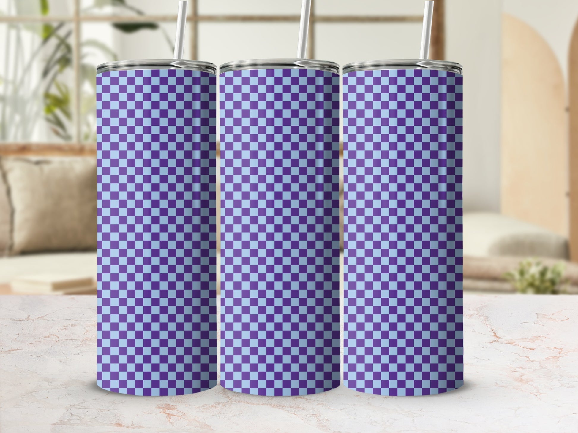 Three purple and light blue checkered tumblers with straws stand on a counter.