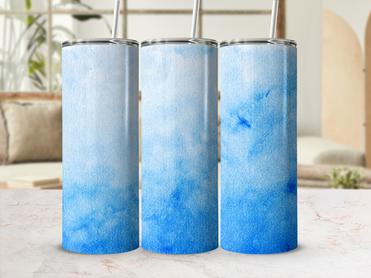 Three blue watercolor gradient tumblers on a marble surface.