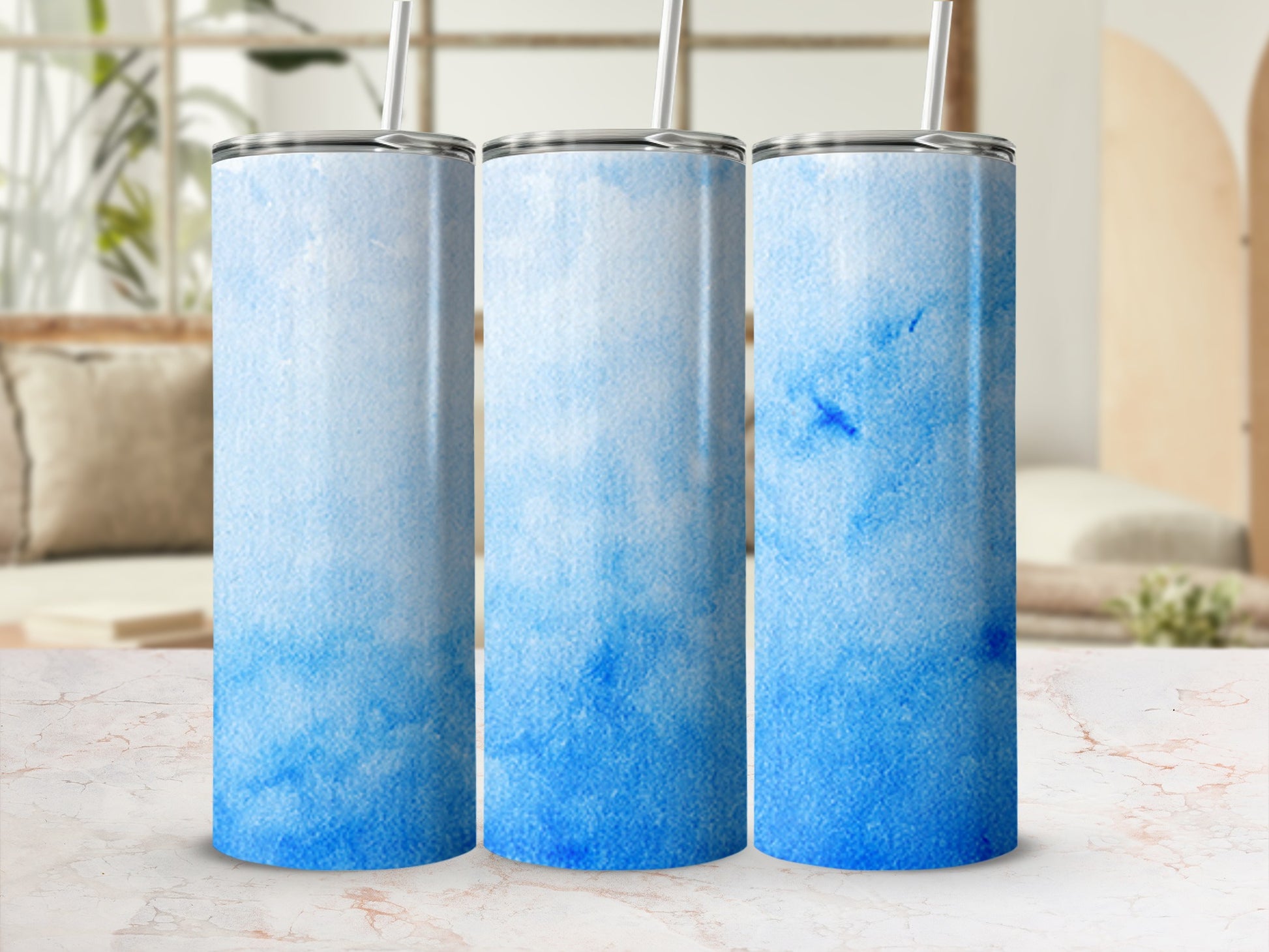 Three blue watercolor gradient tumblers on a marble surface.