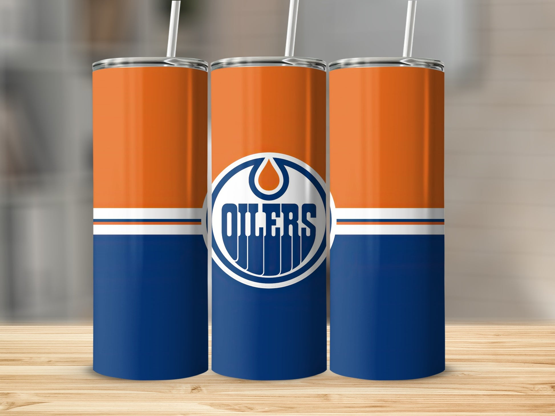 Three Oilers-themed tumblers with orange and blue design and white straws.