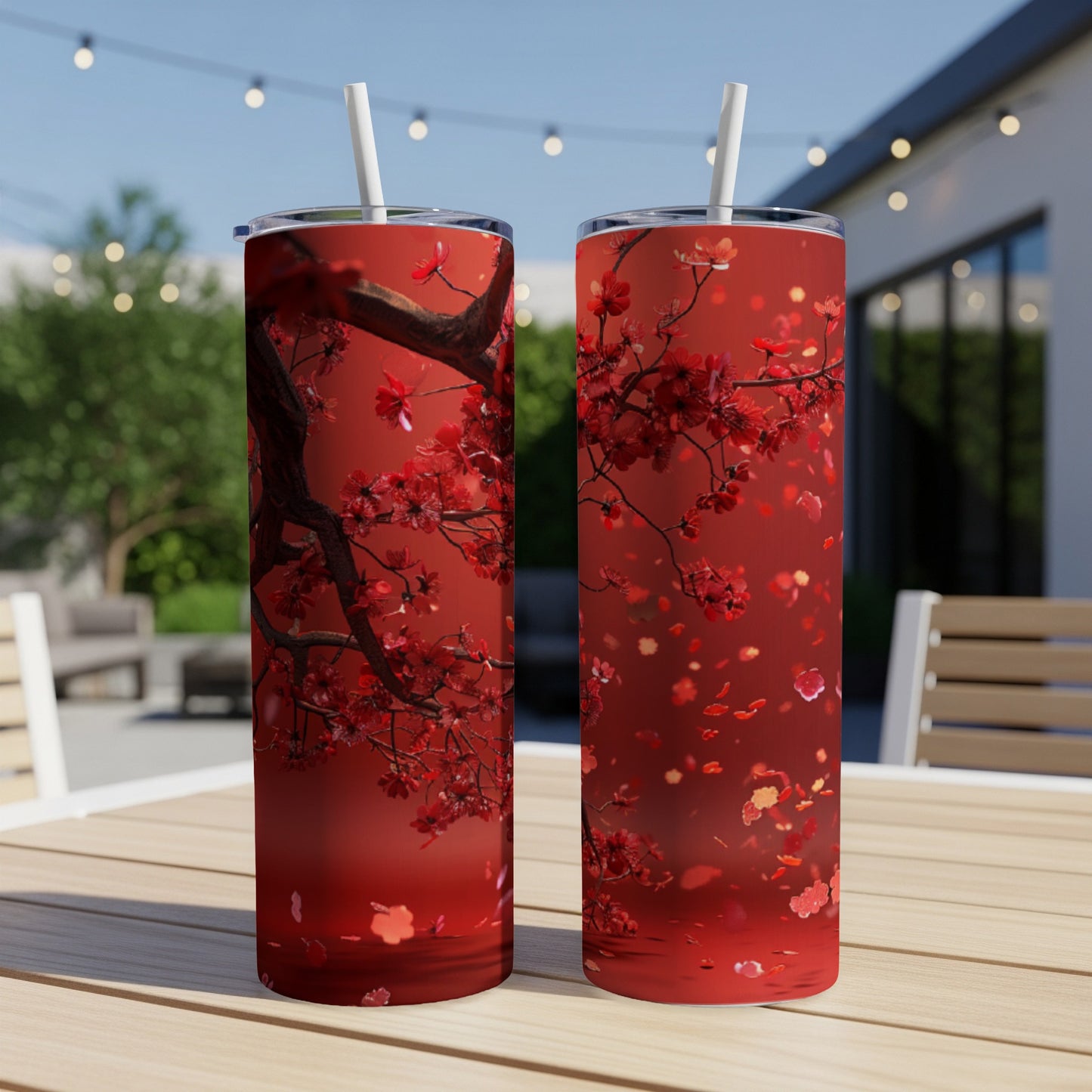 Two tall tumblers with a red floral branch design on an outdoor table.
