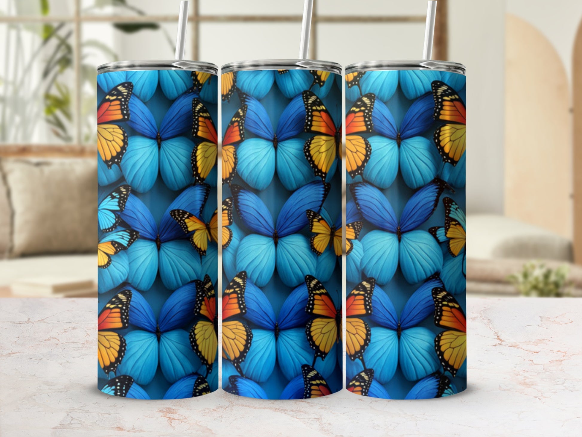 Three tumblers with a vibrant blue butterfly pattern on a marble surface.