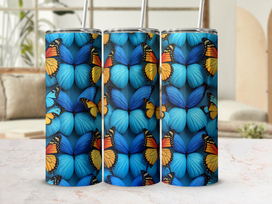 Three tumblers with a vibrant blue butterfly pattern on a marble surface.