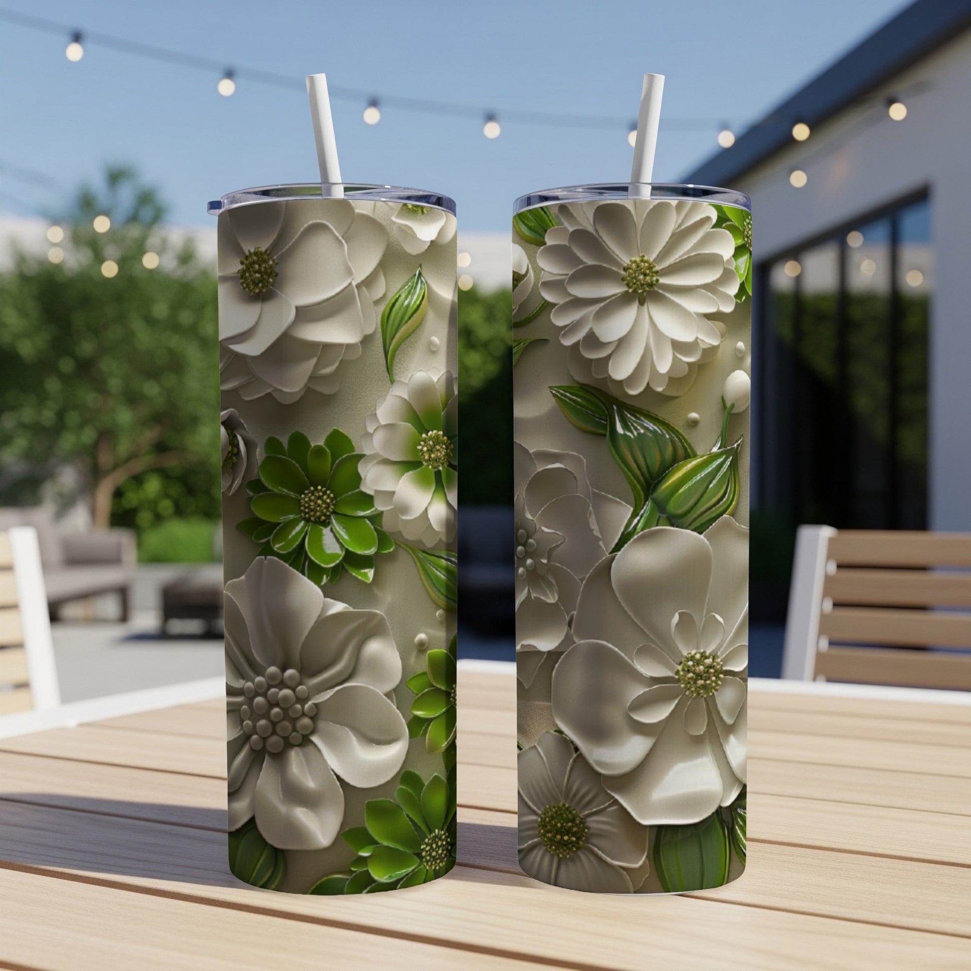 Two white floral patterned tumblers with green accents on a table.