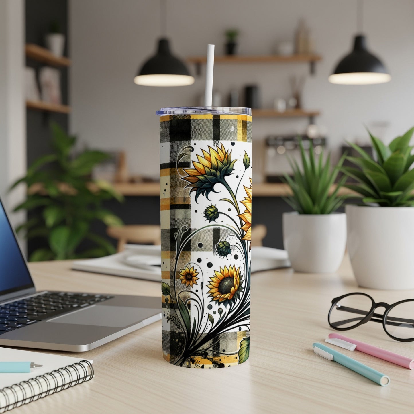 Sunflower tumbler with plaid design on desk with laptop and pens.
