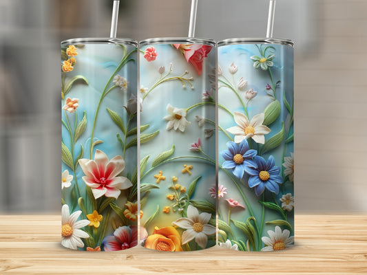 Three tall tumblers with floral designs sit on a wooden surface.