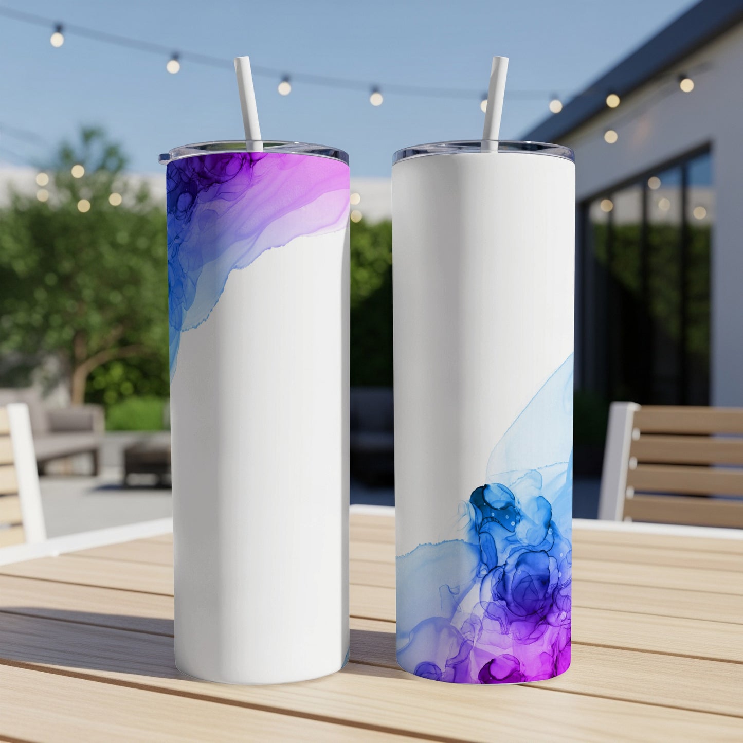 Two white tumblers with abstract blue and purple ink designs and straws.
