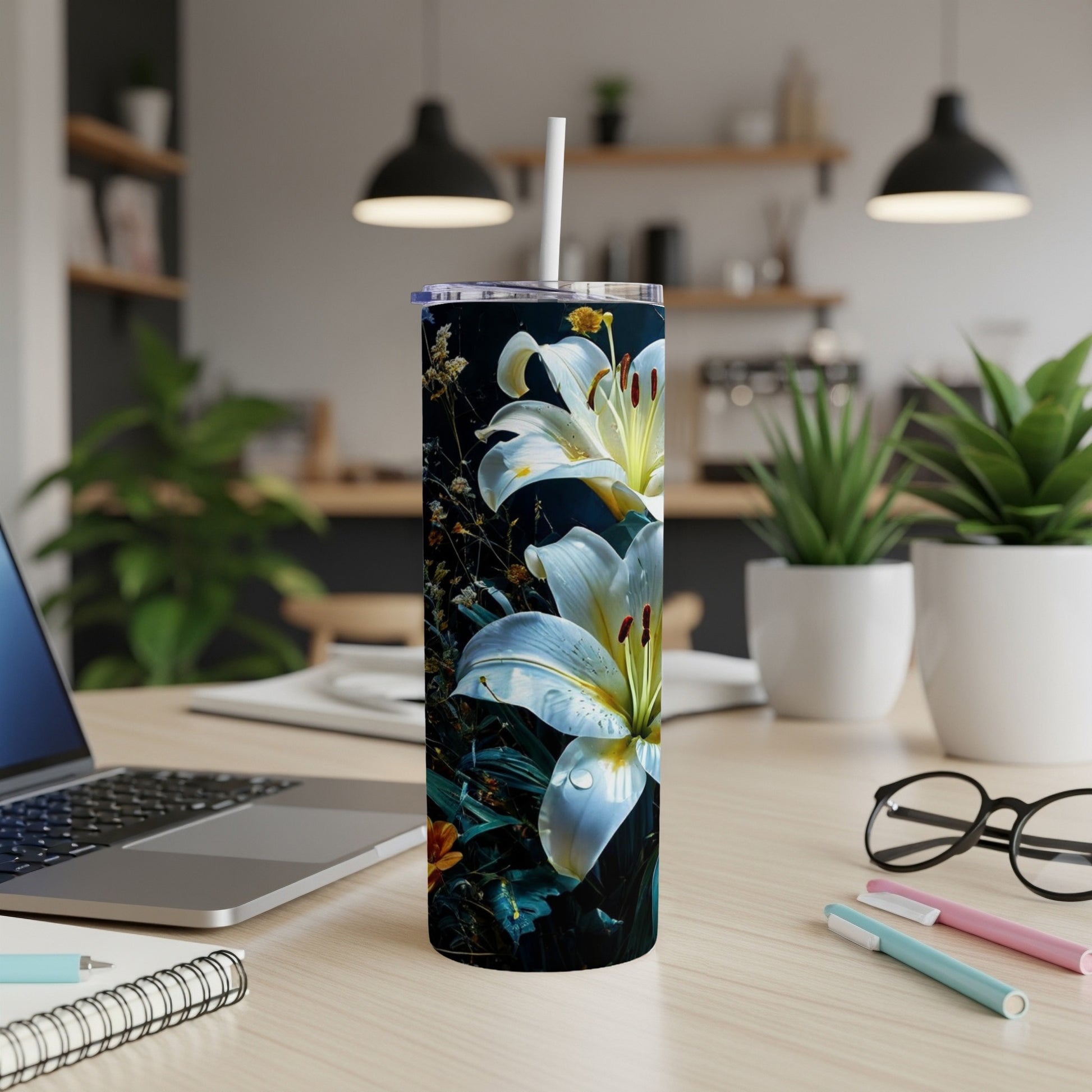 Tall tumbler with white lilies and dark foliage on a wooden desk.
