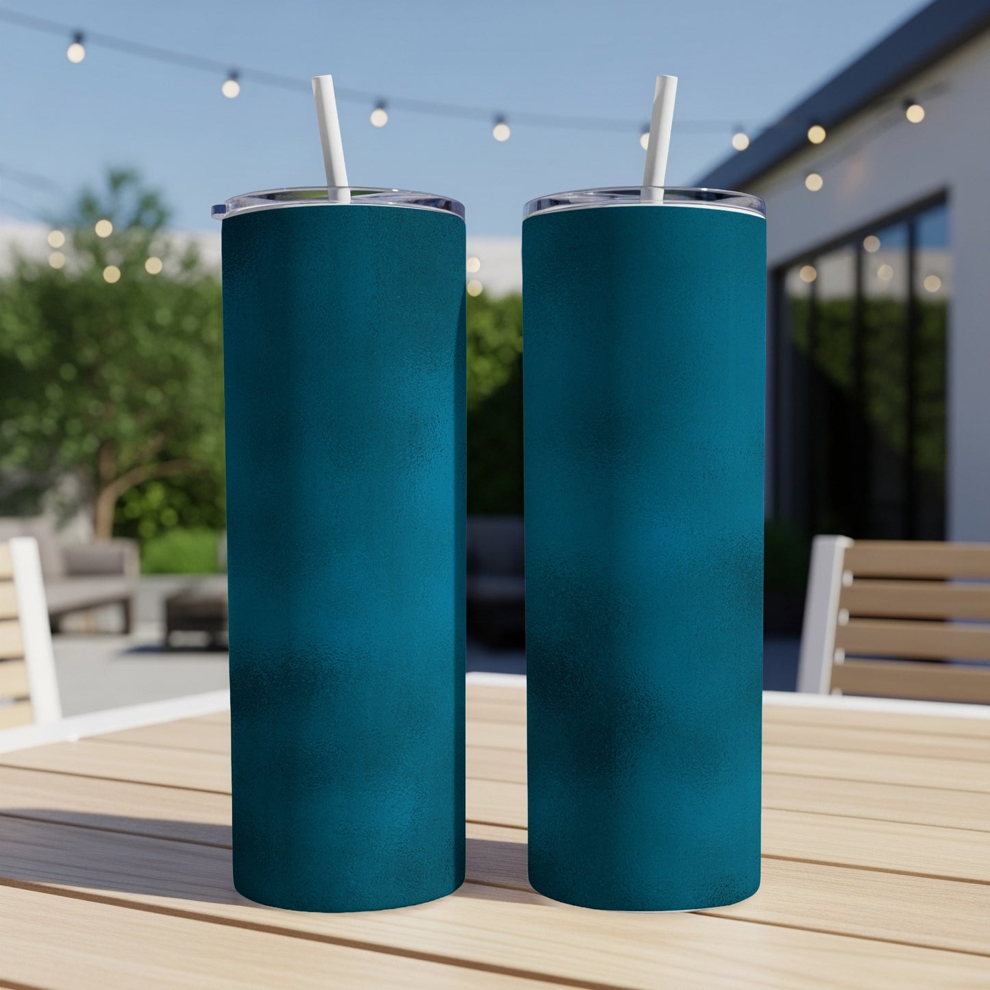 Two teal tumblers with white straws on a wooden table outdoors.