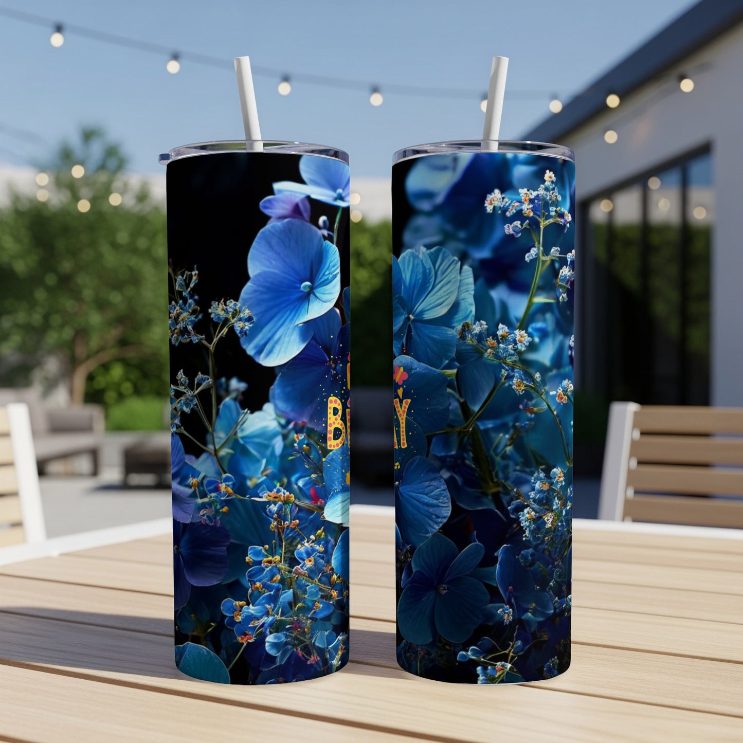 Two blue floral patterned tumblers on a table with a straw.