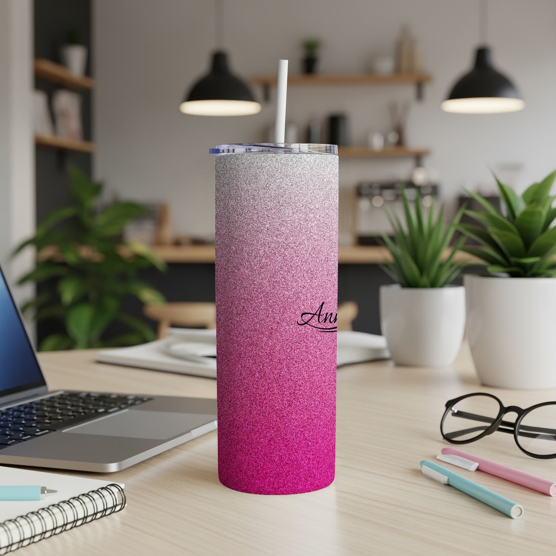 Pink and silver glitter tumbler with a white straw on a desk.