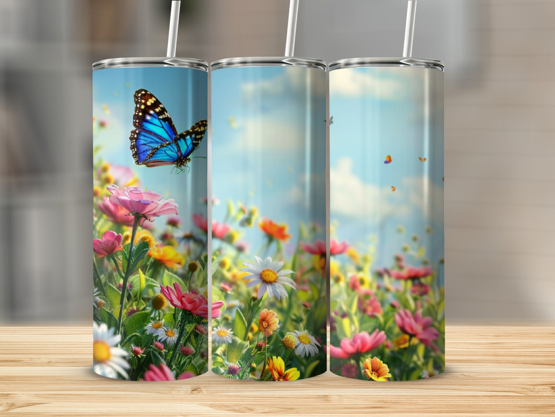 Three tumblers with blue butterfly and wildflowers against a bright sky.