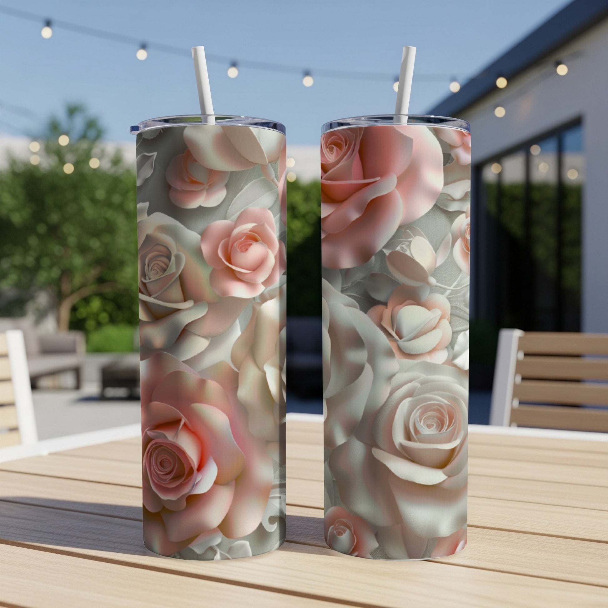 Two tall tumblers with a pink and white floral rose pattern on a patio table.