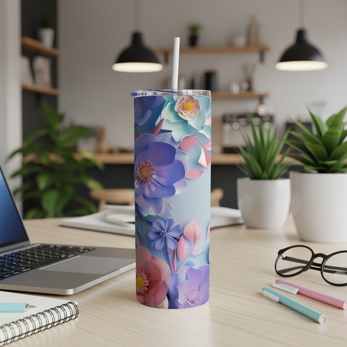Floral tumbler with a light blue background and straw on a desk.