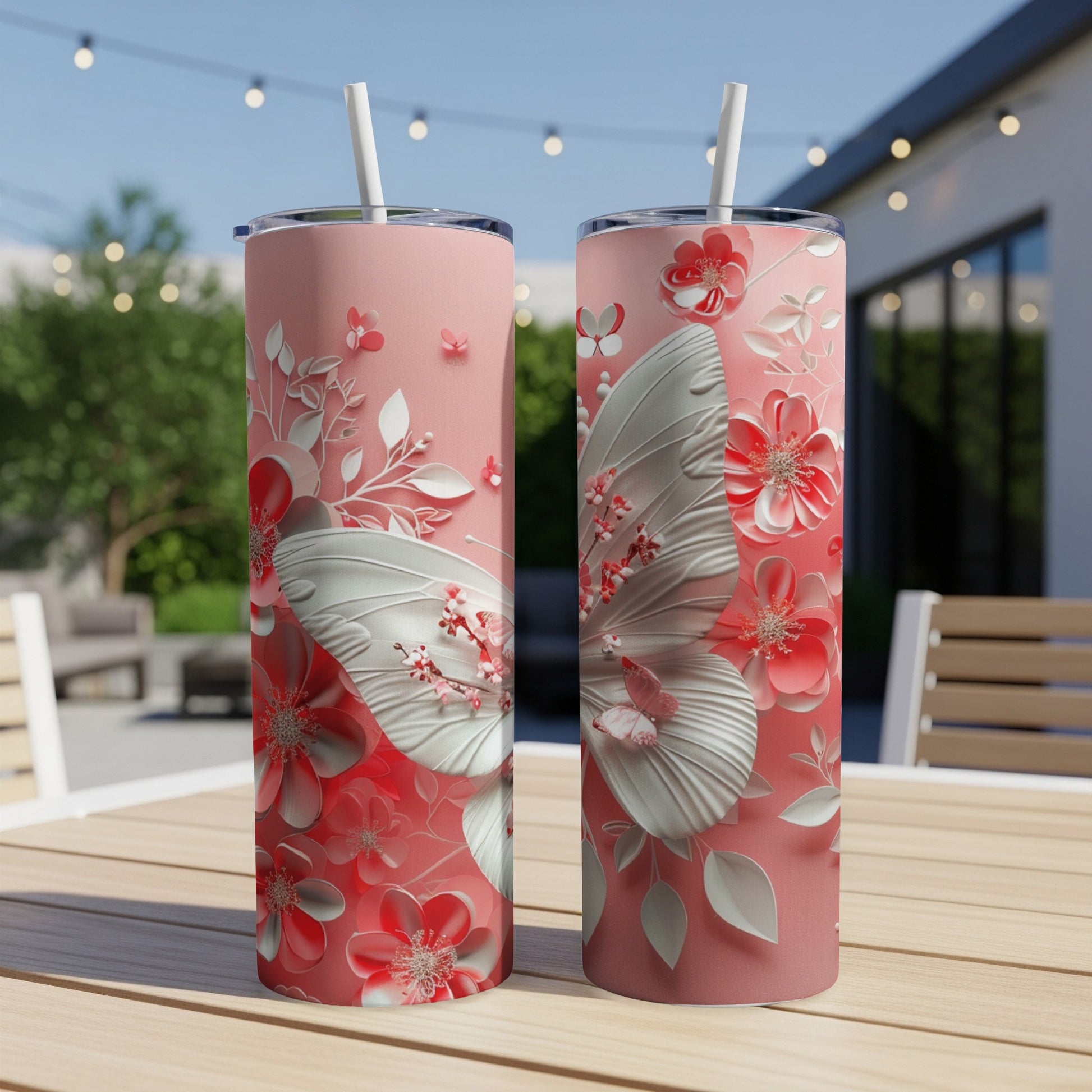 Two pink tumblers with white butterflies and floral designs on a table.