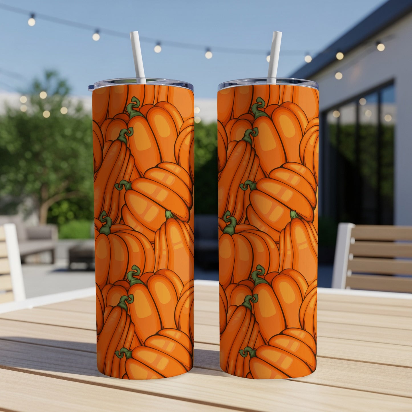 Two tumblers with a repeating pattern of cartoon pumpkins on a wooden table.