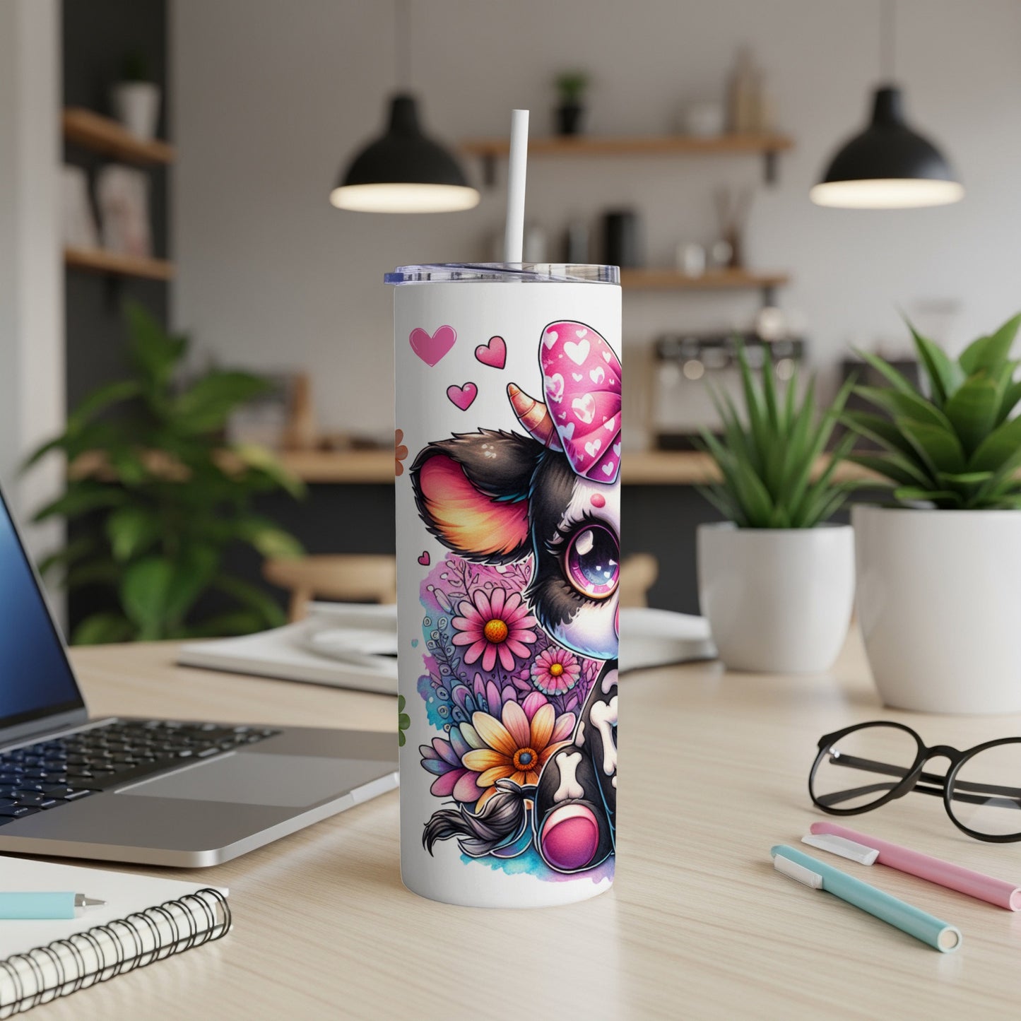 White tumbler with cute cartoon cow, flowers, and pink bow on desk.