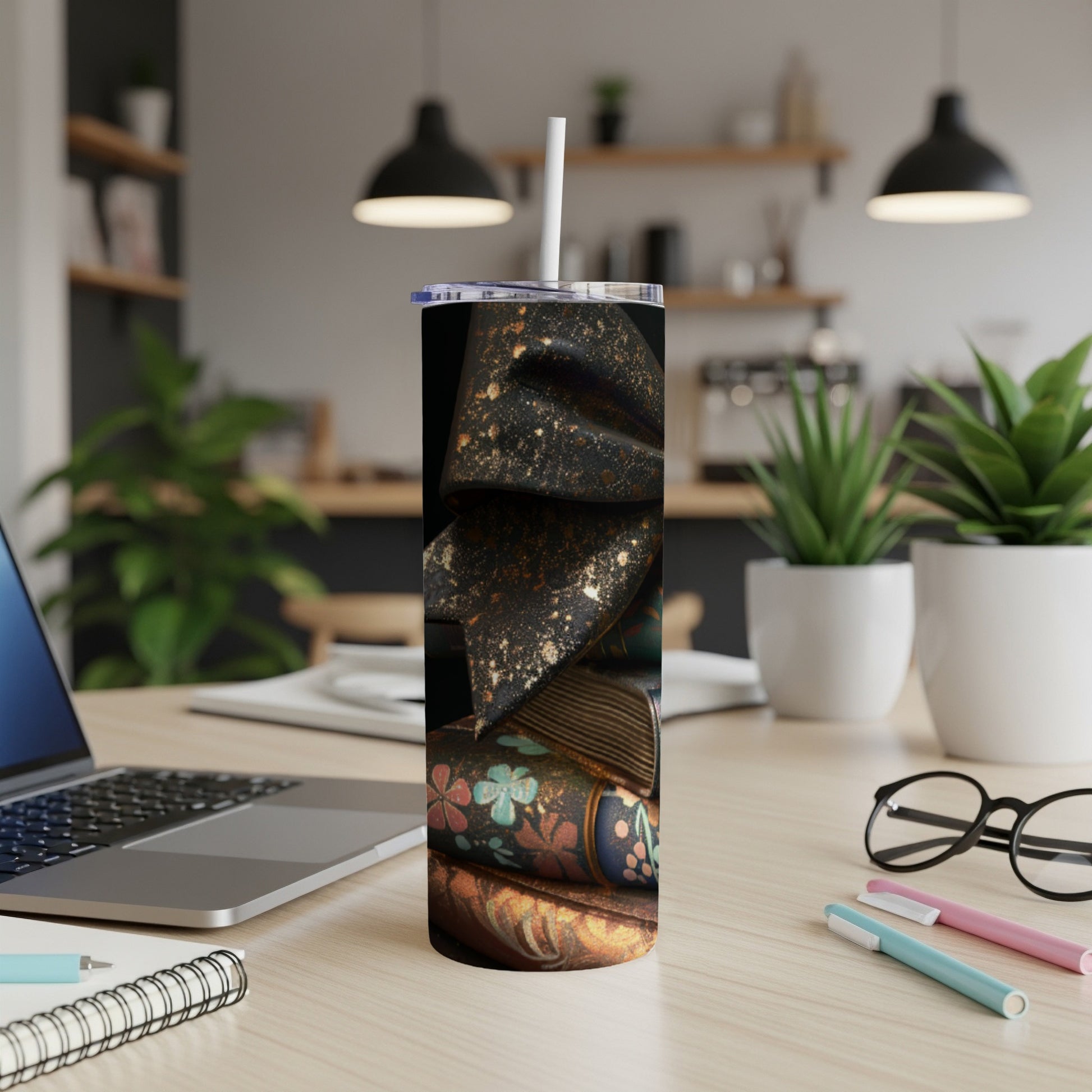 Tumbler with antique books and floral pattern on a desk.