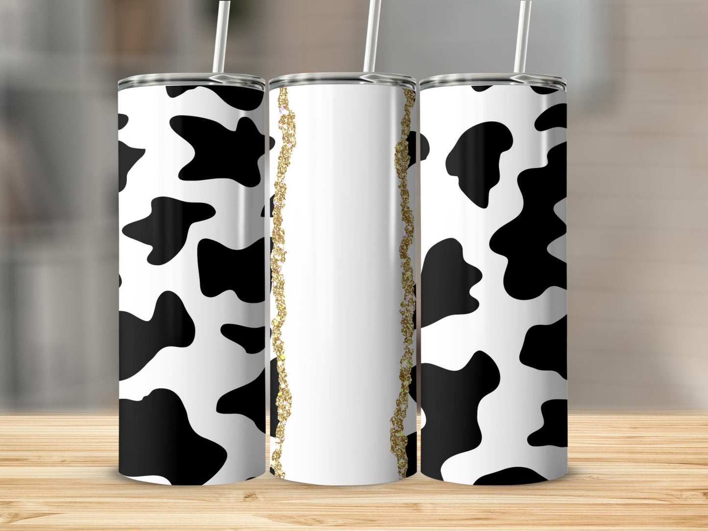 Three tumblers with black and white cow print and gold glitter detail.