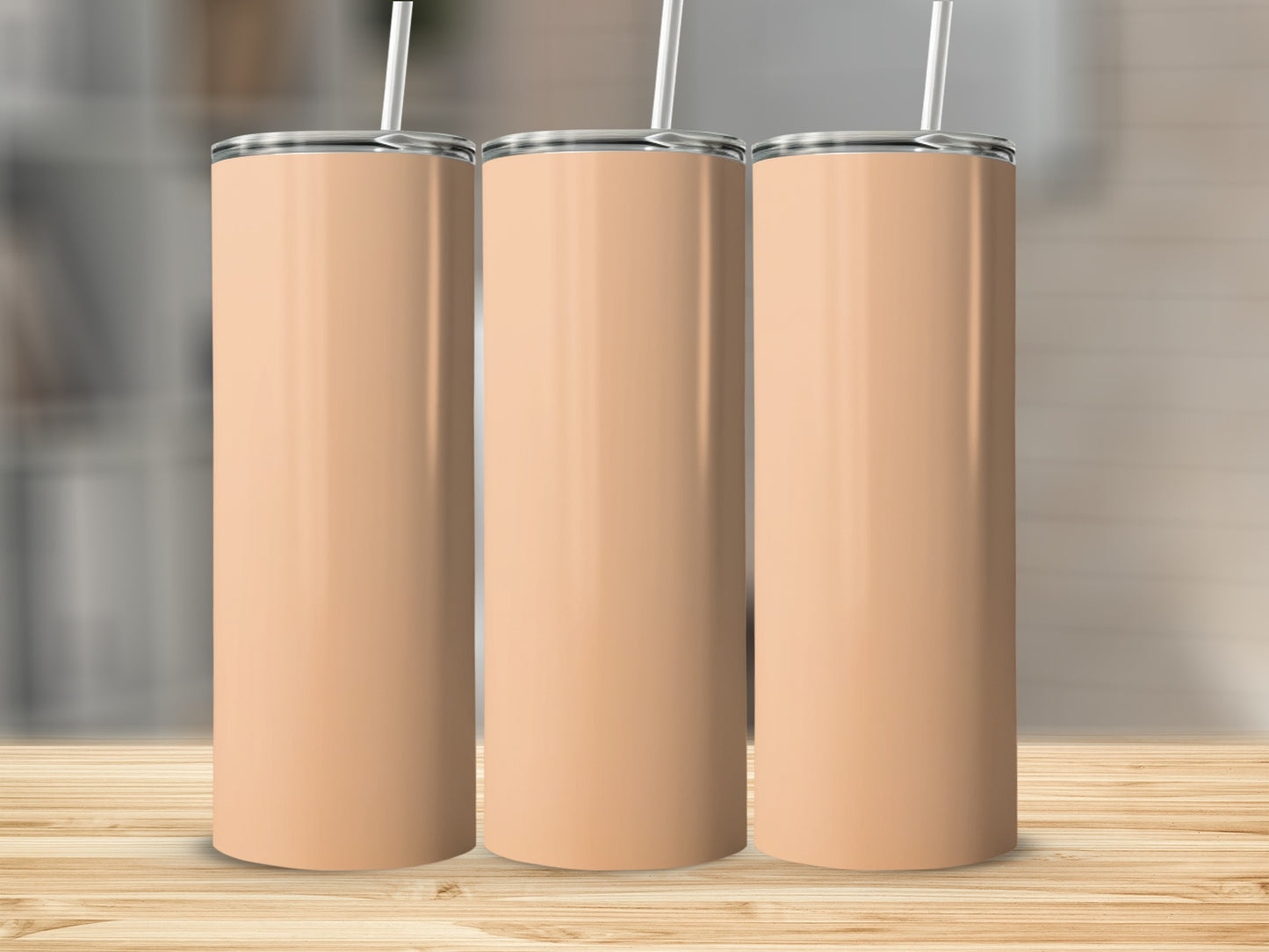 Three tall, light peach colored tumblers with silver straws stand on a wooden surface.