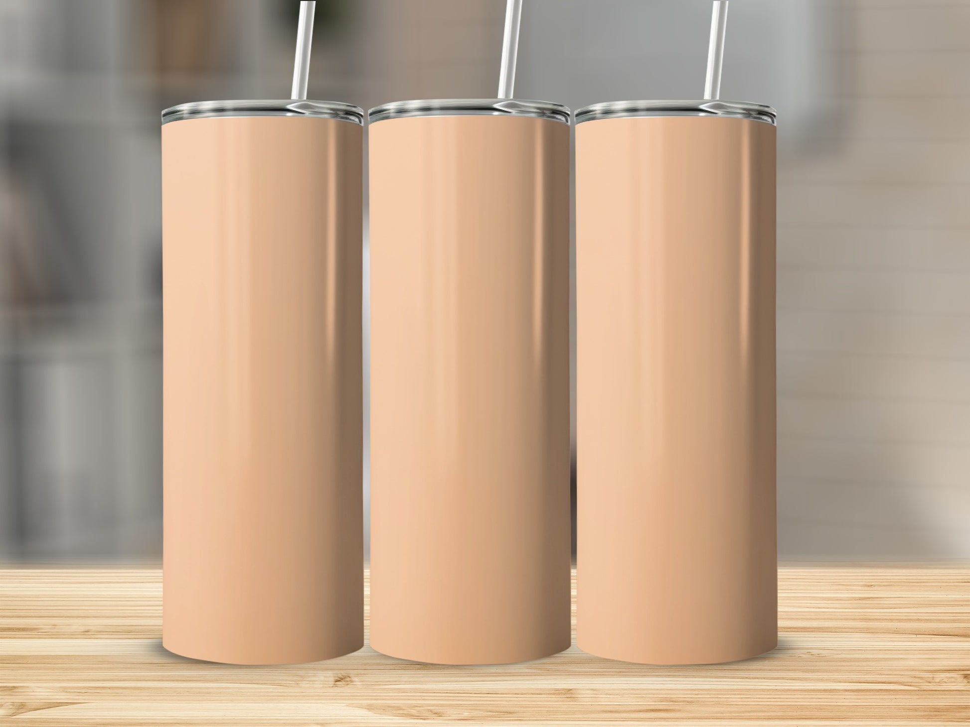 Three tall, light peach colored tumblers with silver straws stand on a wooden surface.