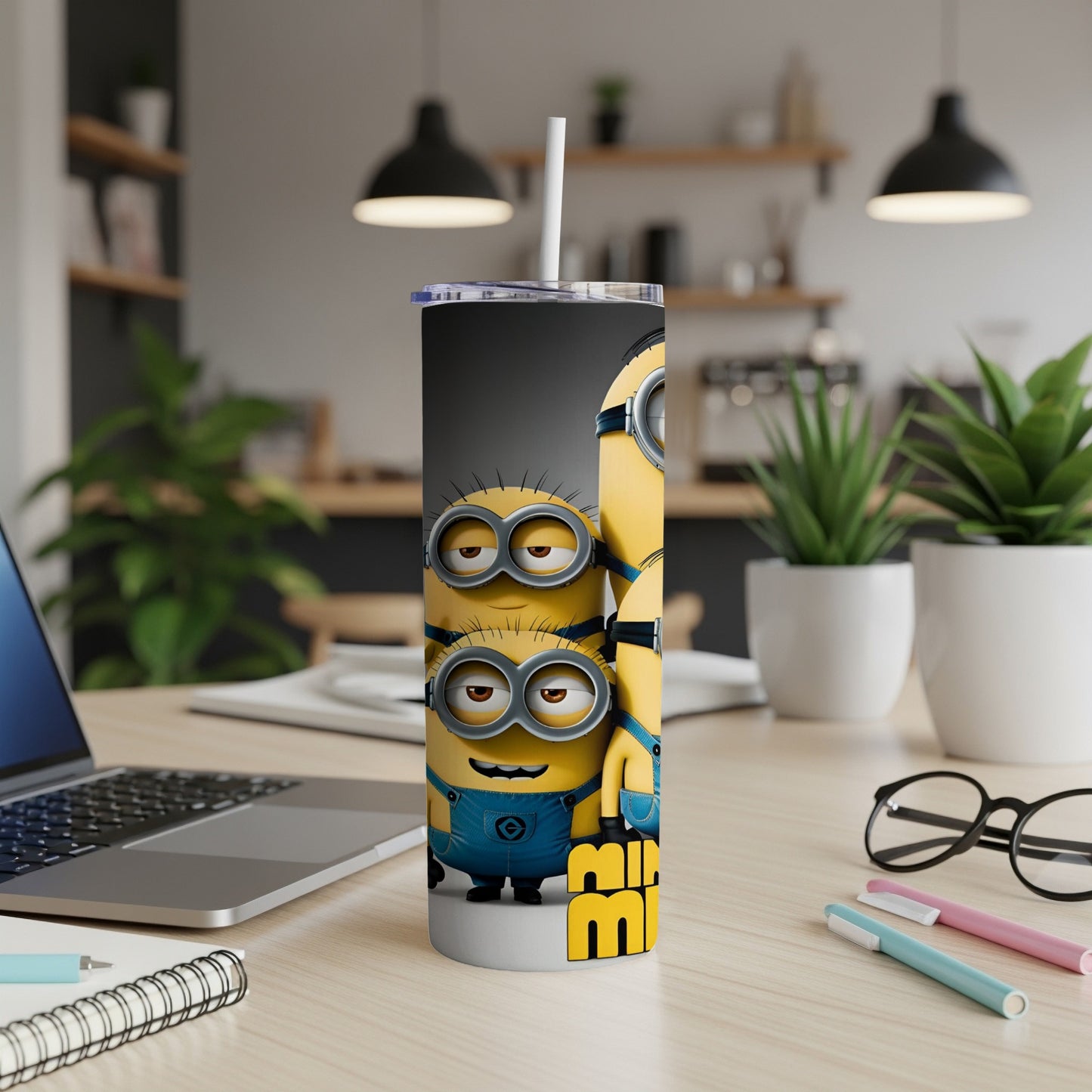 Minions characters on a tall tumbler with a straw on a desk.