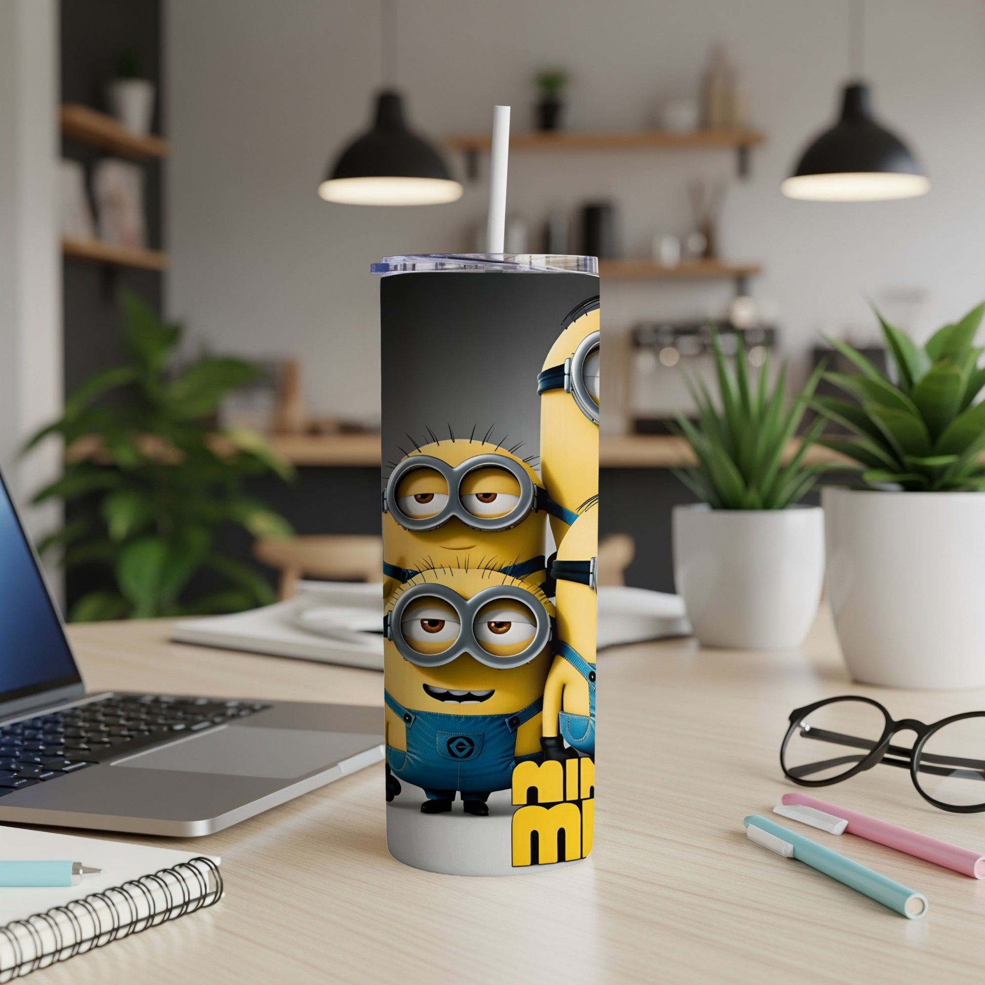 Minions characters on a tall tumbler with a straw on a desk.
