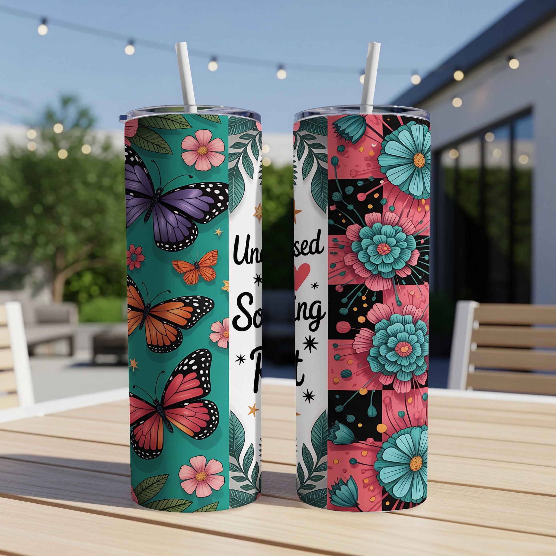 Two tumblers on a table with floral and butterfly designs, one reads "Unbossed & Unbothered".
