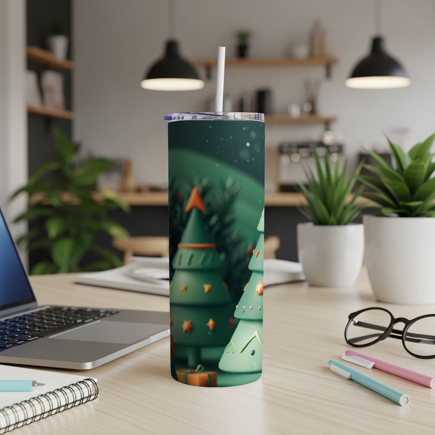 Green Christmas tree tumbler with straw on desk next to laptop.