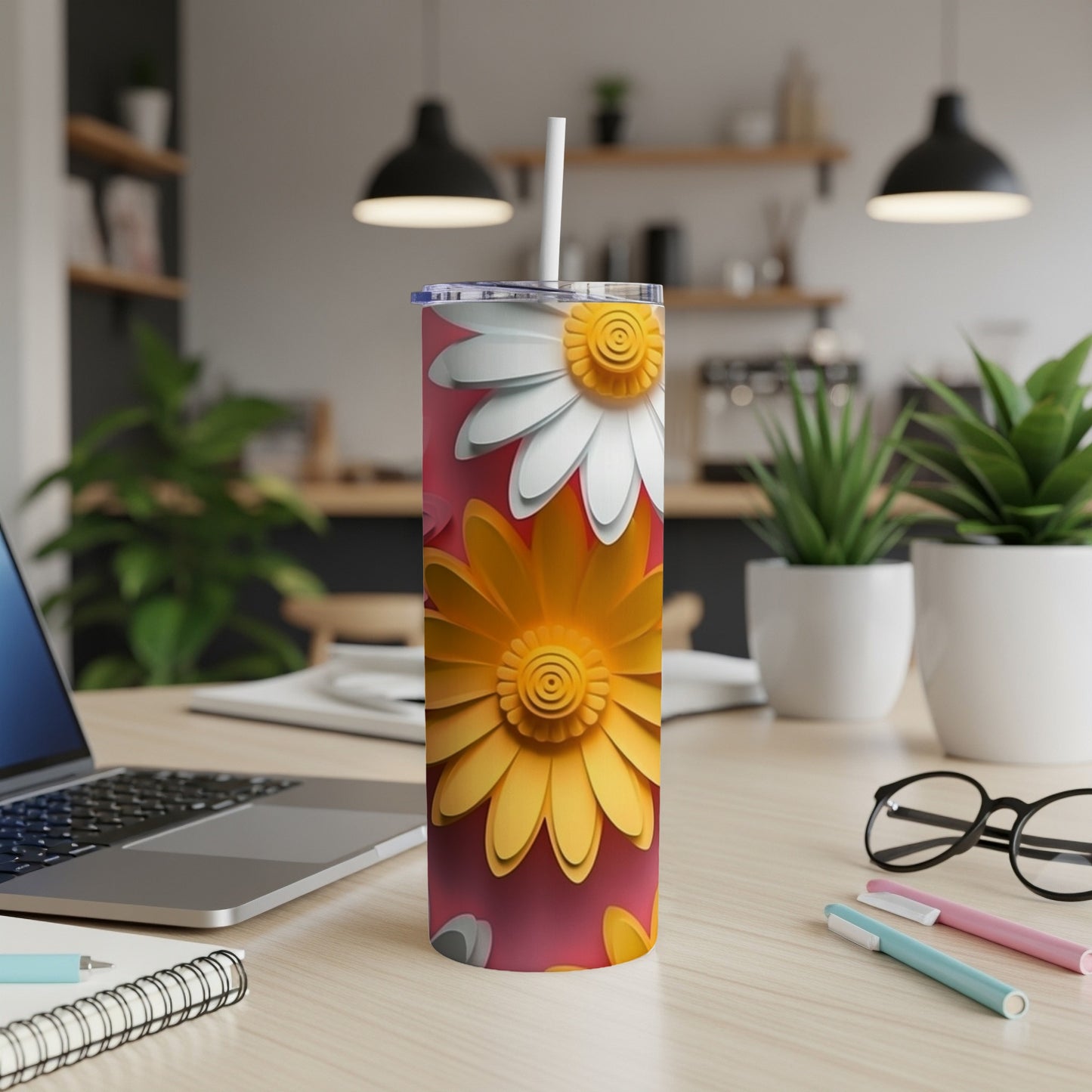 Tall tumbler with yellow and white daisy designs on a desk.