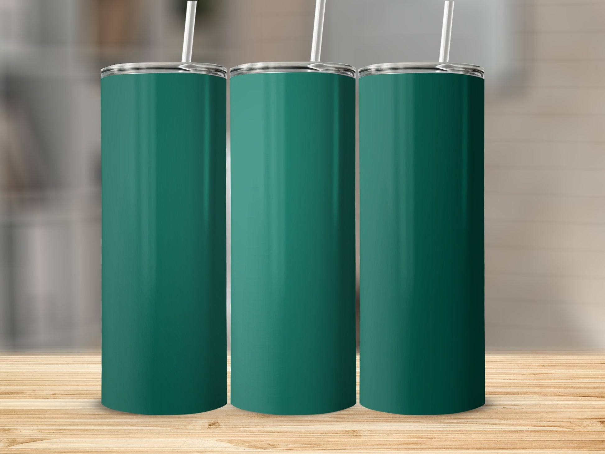Three teal tumblers with white straws stand on a wooden surface.