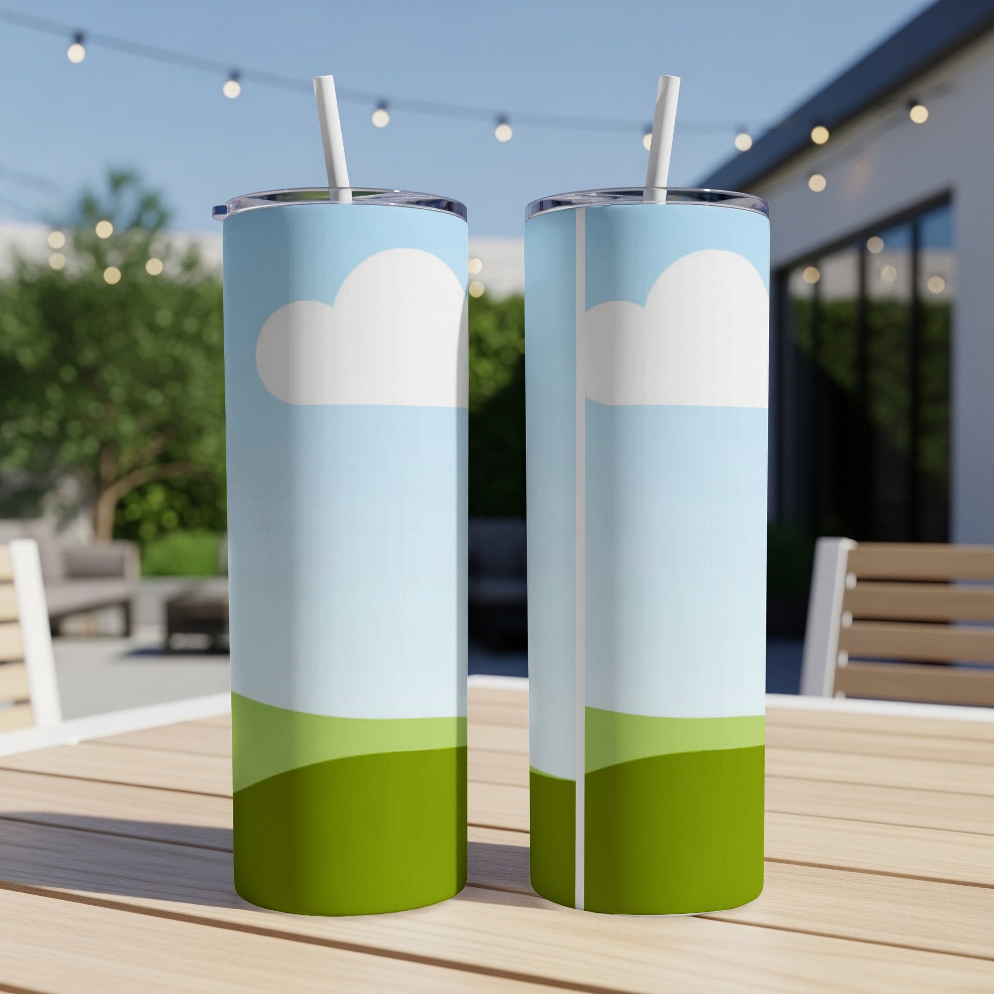 Two tumblers with a sky and rolling green hills design sit on a table.