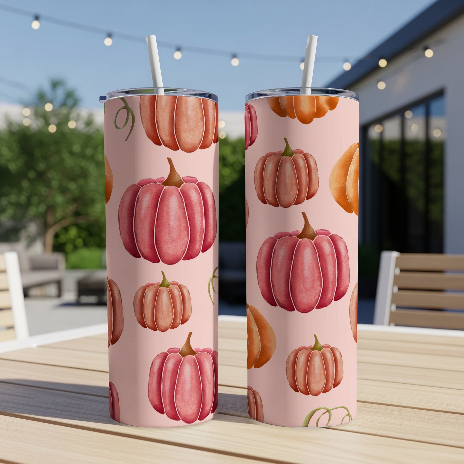Two pink tumblers with a repeating pattern of cartoon pumpkins.