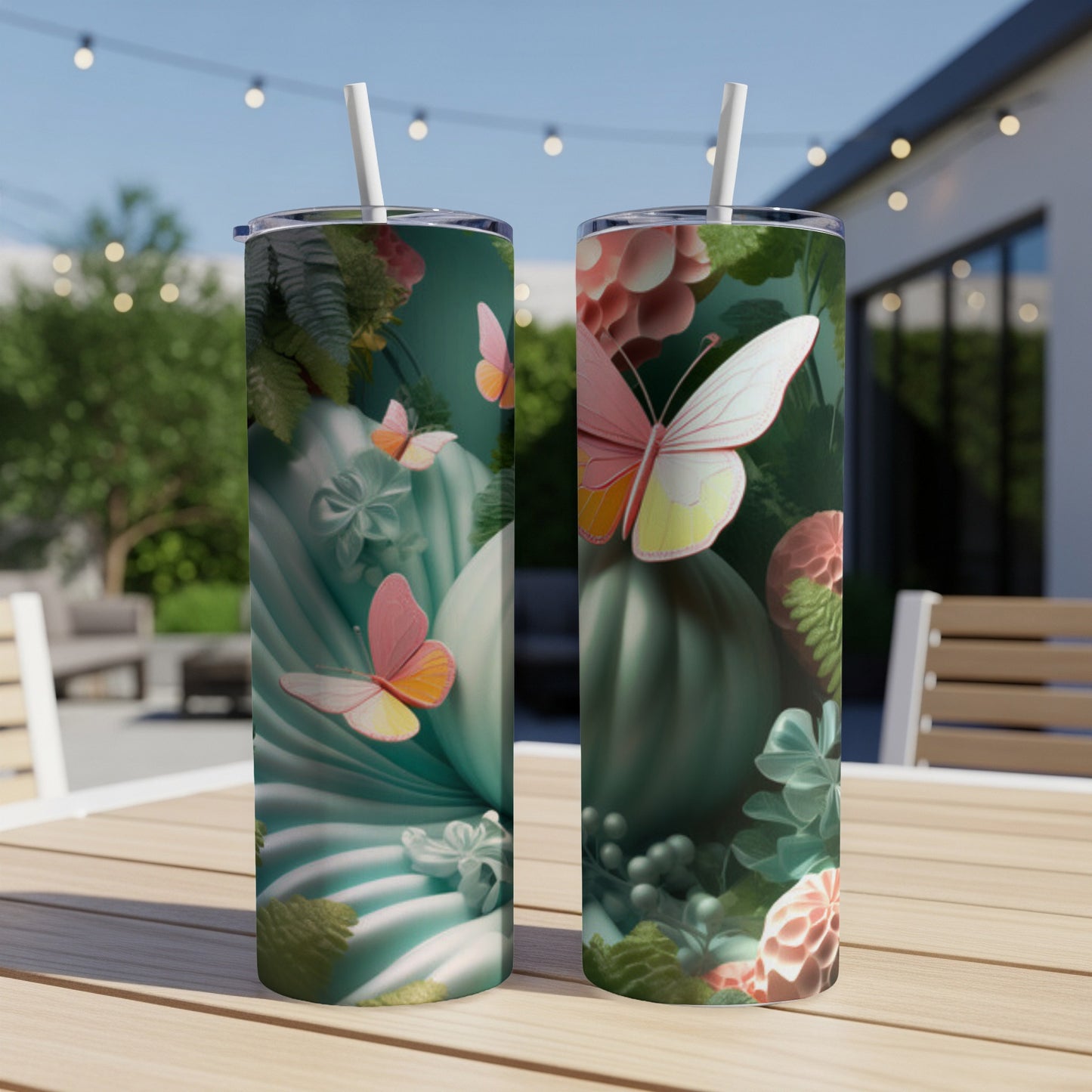Two tumblers with pink butterflies and green floral designs on a patio table.