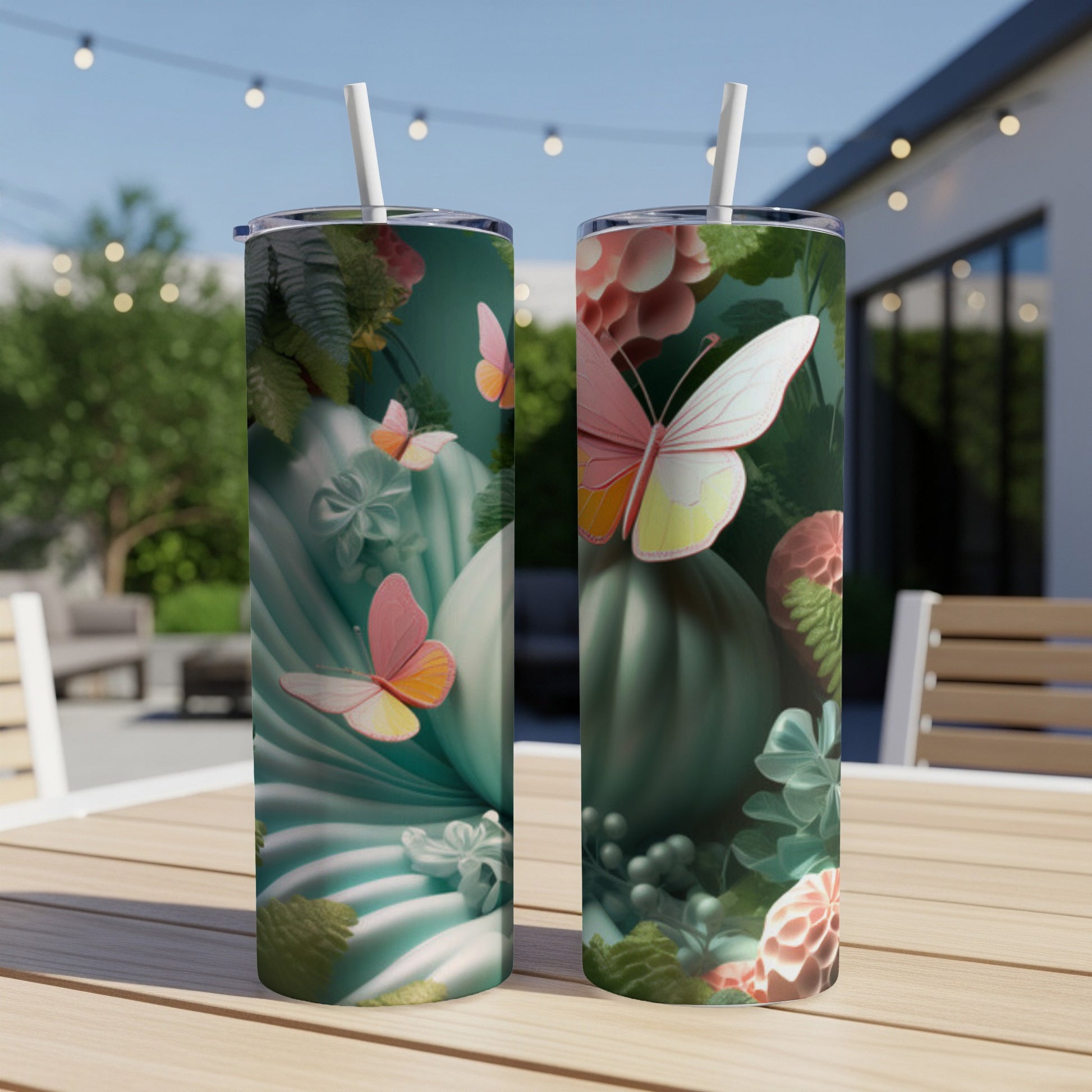 Two tumblers with pink butterflies and green floral designs on a patio table.