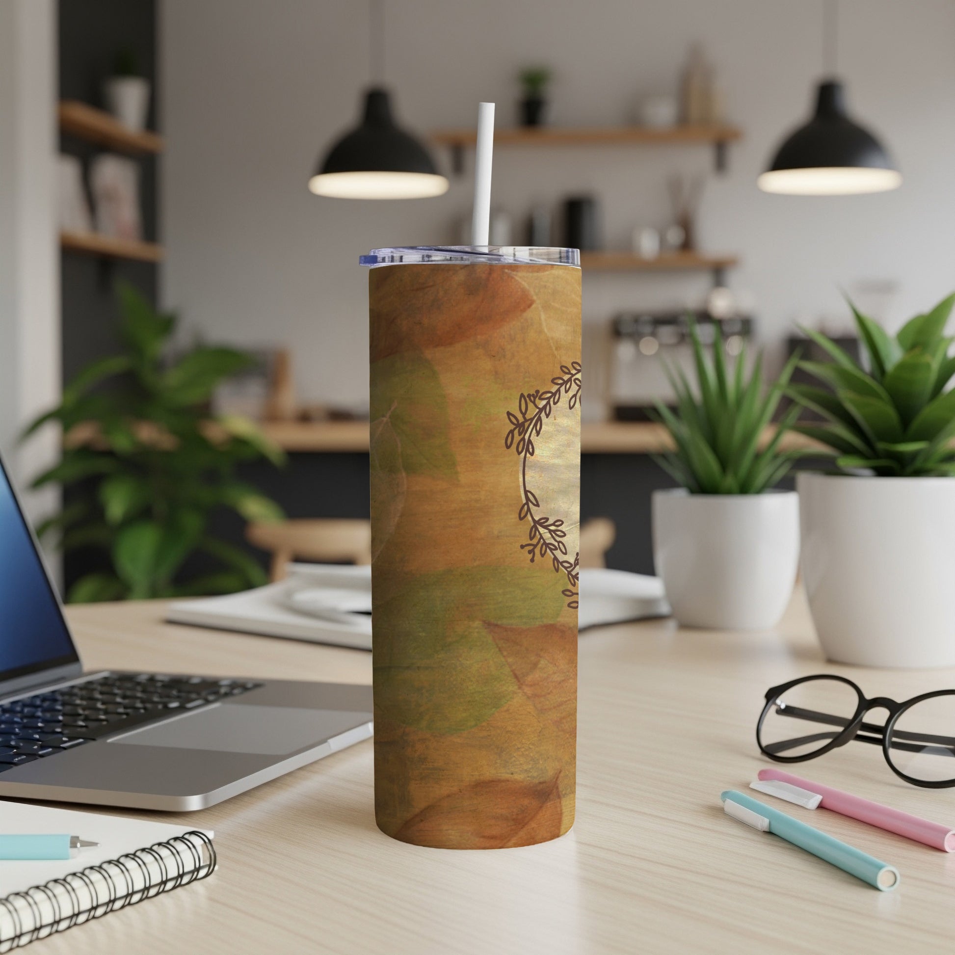 Fall leaf pattern tumbler with straw on desk.