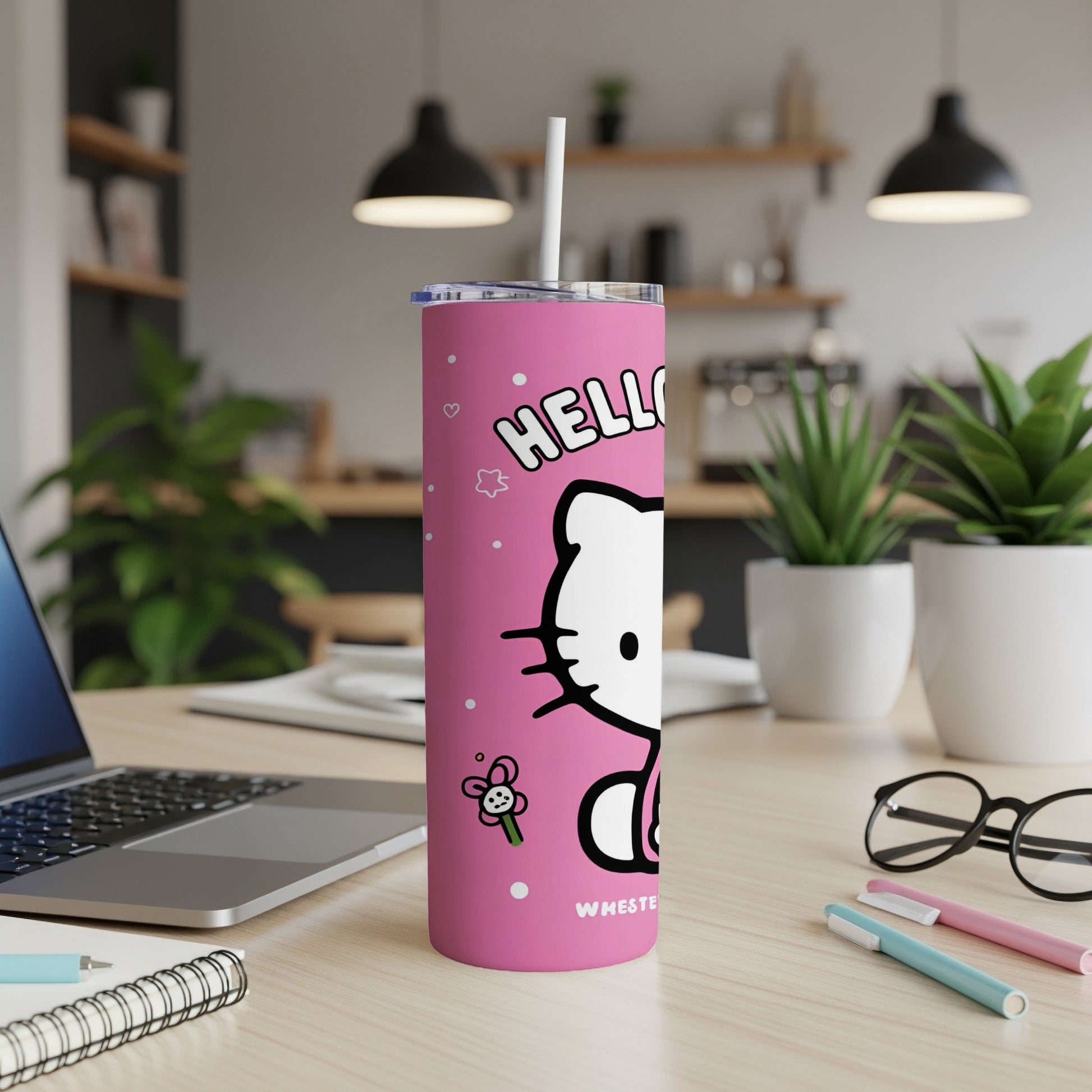 Pink Hello Kitty tumbler with straw, laptop, and pens on a desk.