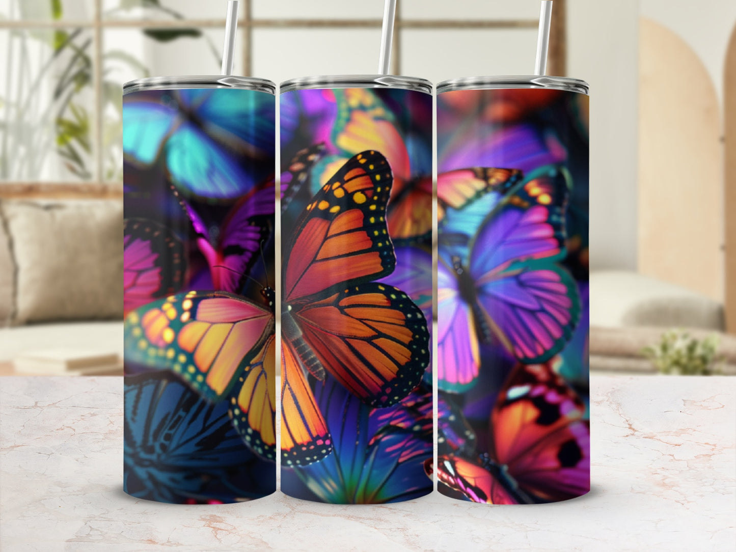 Three tumblers with vibrant butterfly designs displayed on a marble surface.