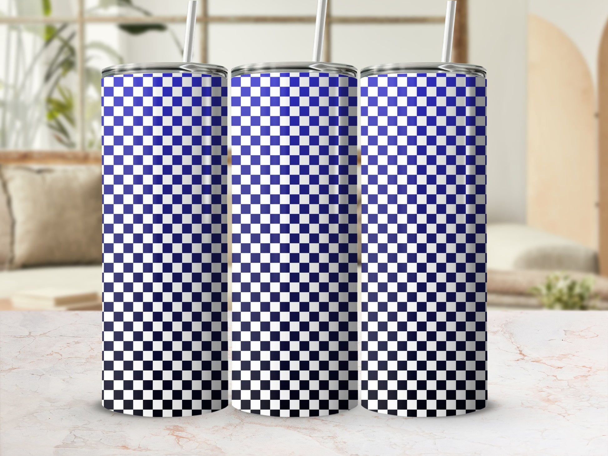 Three blue and white checkered gradient tumblers with straws on a marble surface.