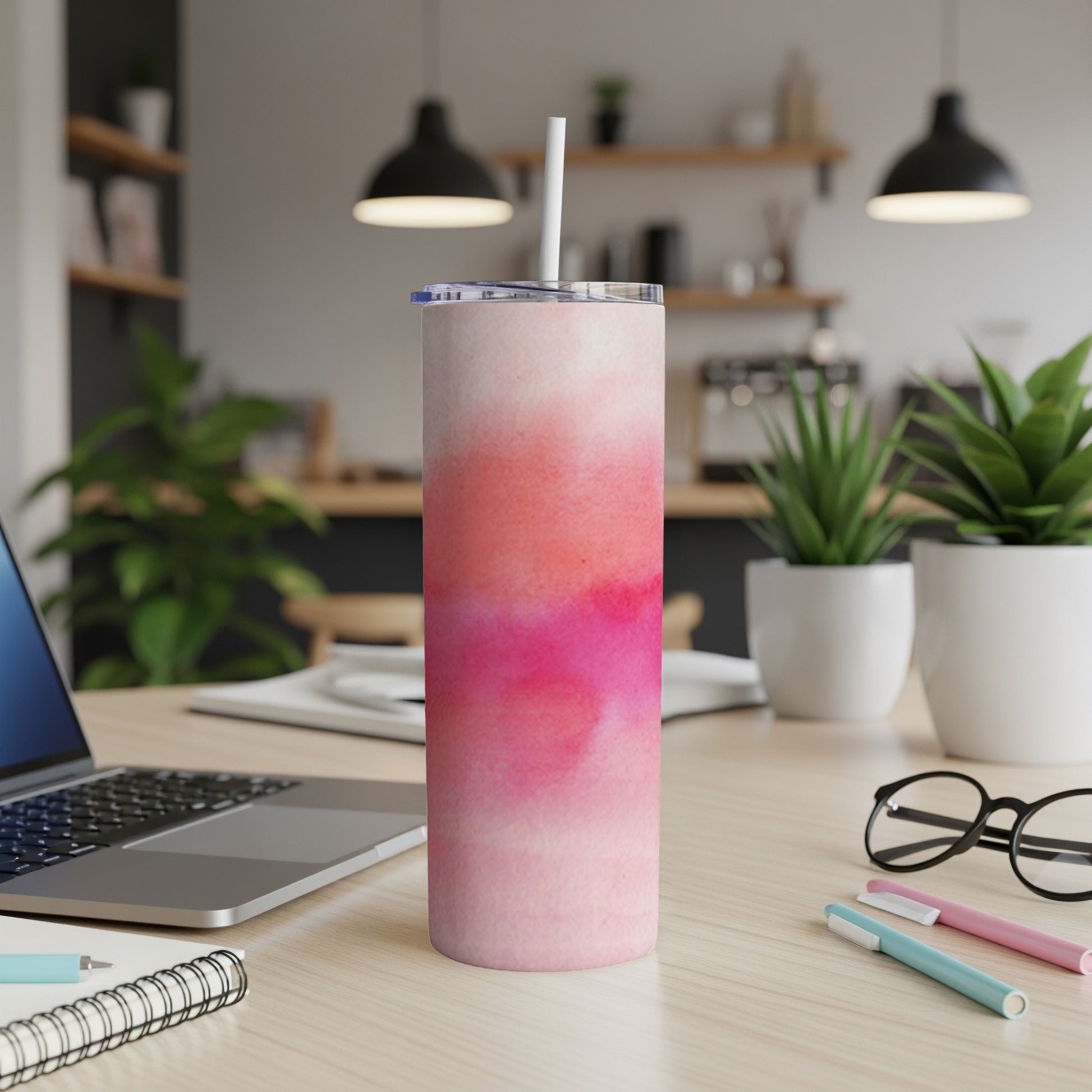 Pink watercolor gradient skinny tumbler with straw on desk.