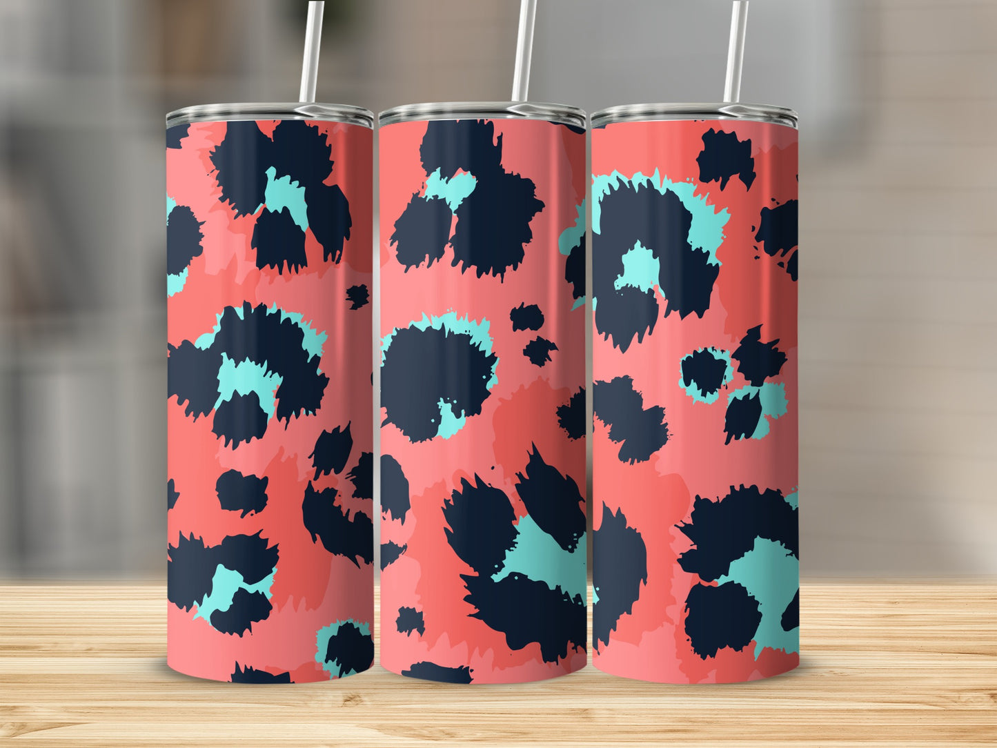 Three tall tumblers with a coral background and abstract navy and teal leopard print pattern.