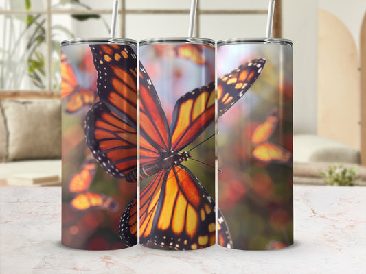 Three tumblers featuring monarch butterflies against a blurred background.