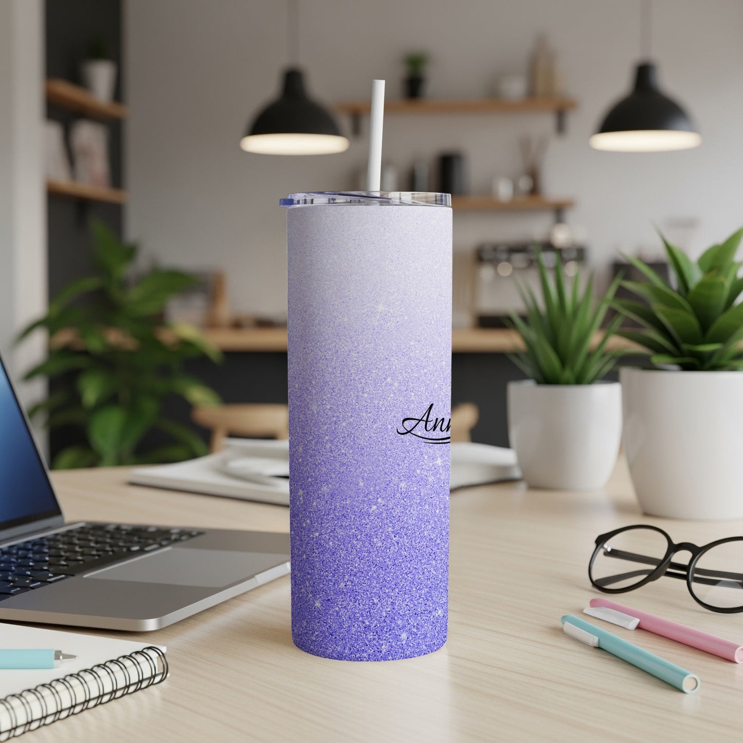 Purple glitter tumbler with personalized "Anna" text on a desk.