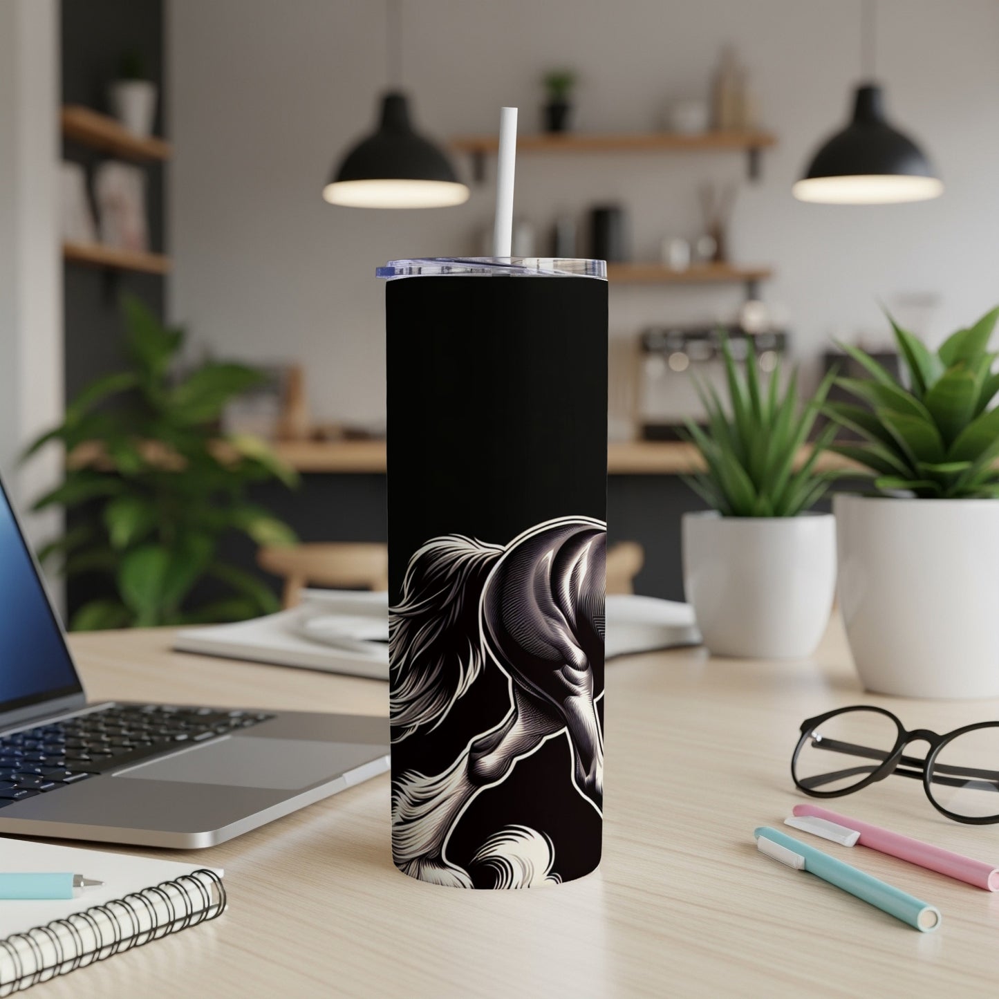 Black tumbler with stylized white horse head design, on a desk.
