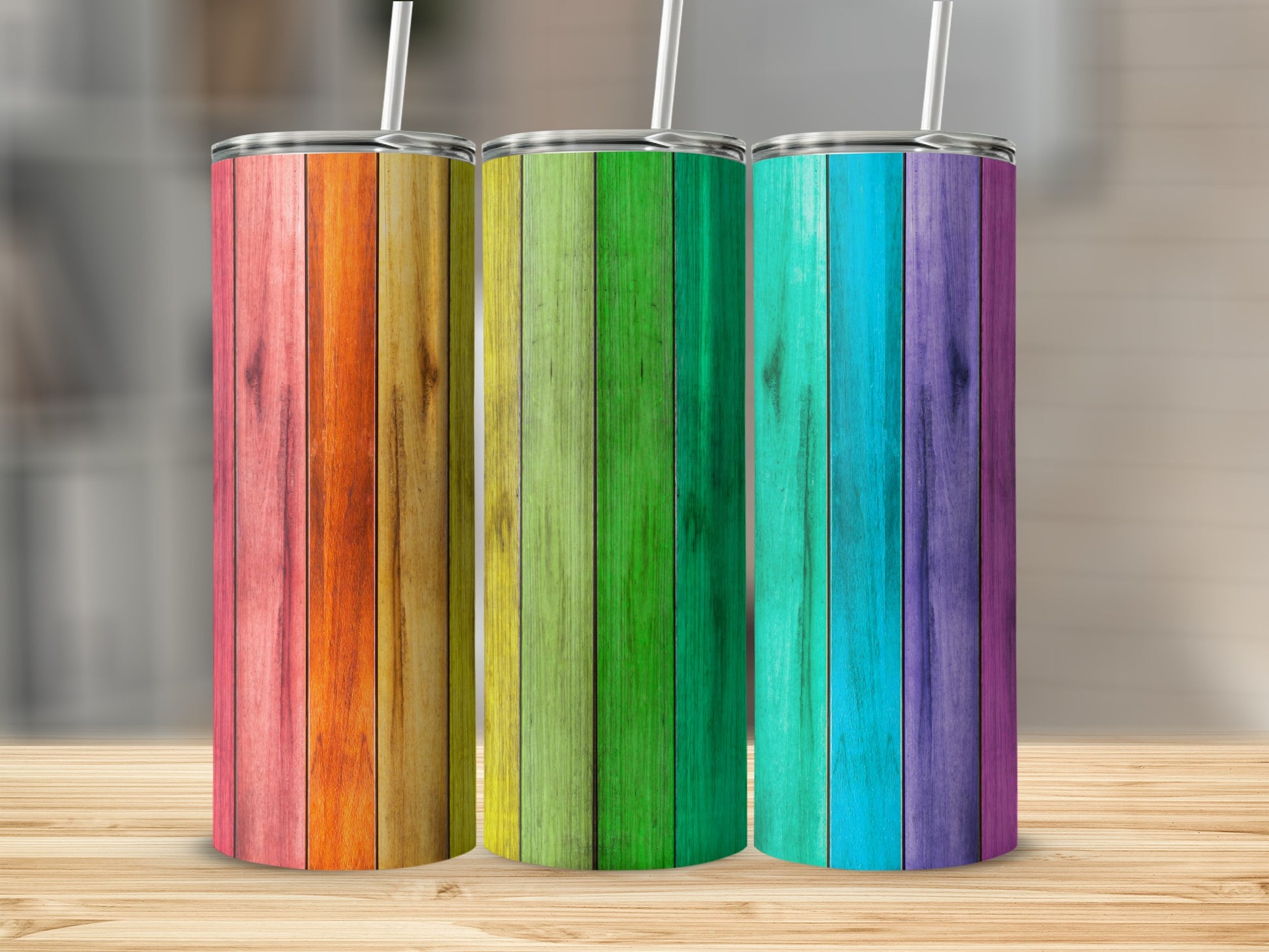 Three tall tumblers with rainbow wood grain patterns stand on a wooden surface.