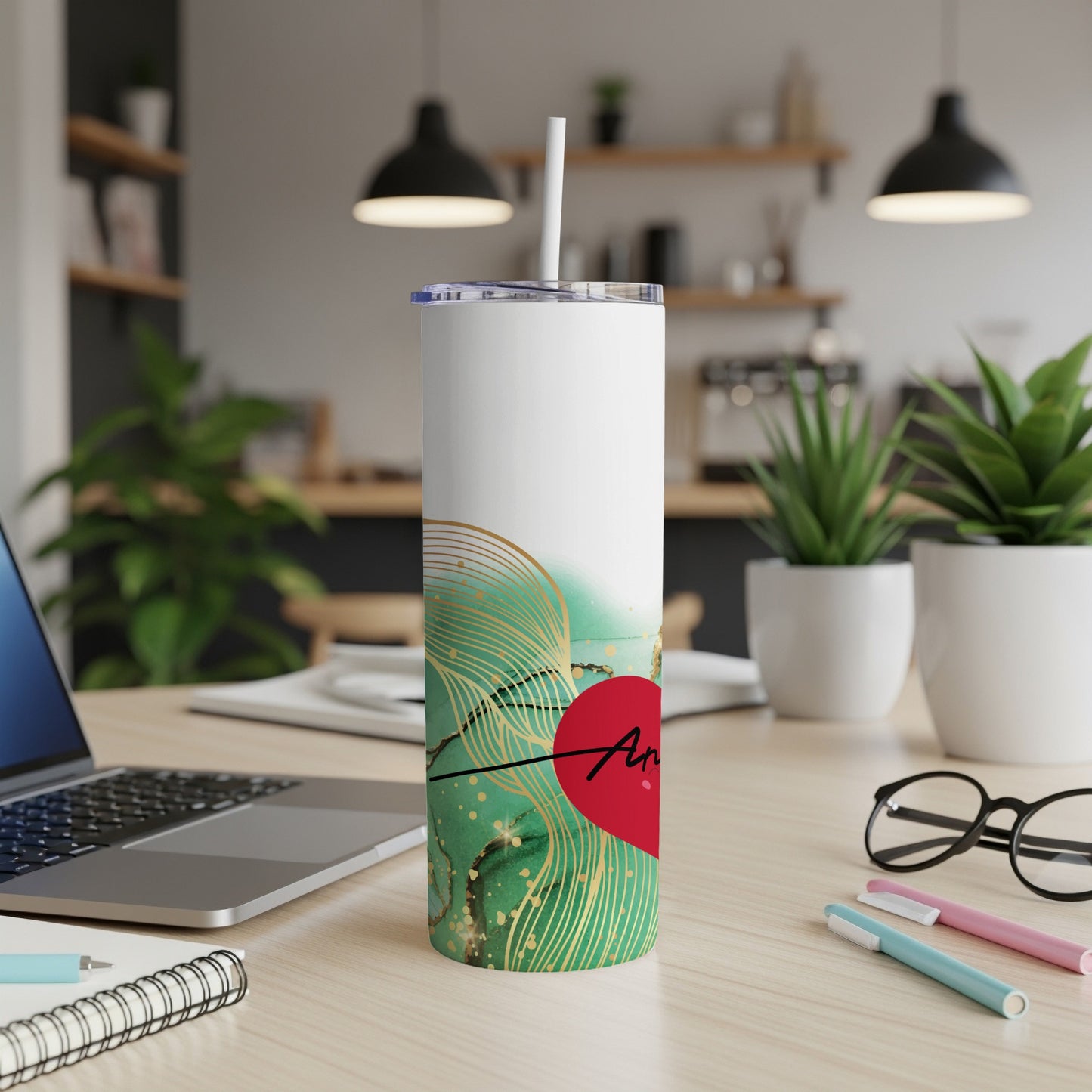 White tumbler with green and gold abstract design and "Amor" in red heart.