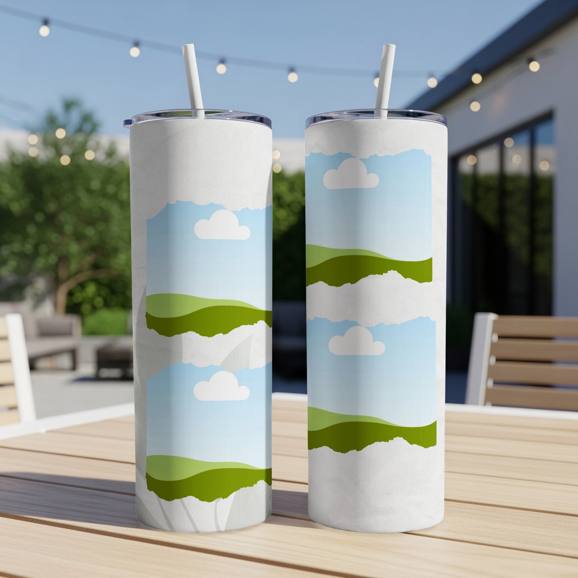 Two tumblers with a torn paper effect revealing a sky, clouds, and green hills design.