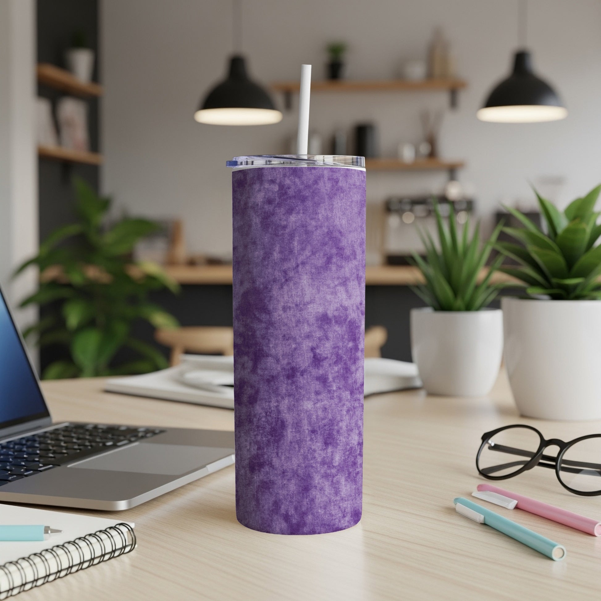Purple textured tumbler with straw on a desk next to a laptop.